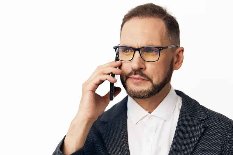 A focused business professional man on a vibrant isolated colored background, speaking on a mobile phone with calm confidence, conveying leadership and clear communication.