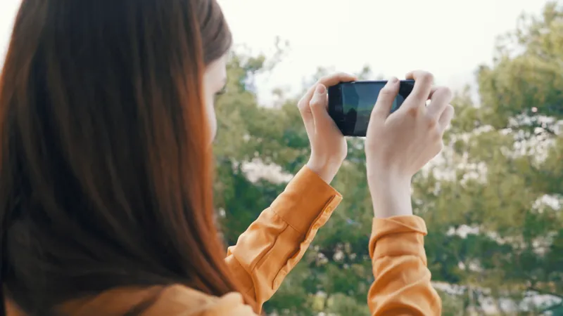 Женщина с телефоном в руке фотографирует природу на камеру