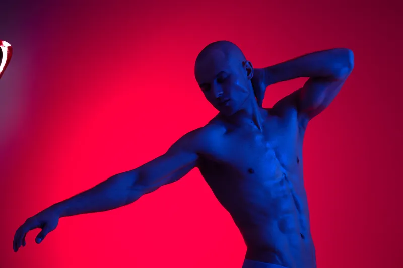 Artistic portrait of a man in blue light, showcasing a dynamic pose and expressive emotions, emphasizing strength and confidence in a vibrant atmosphere.