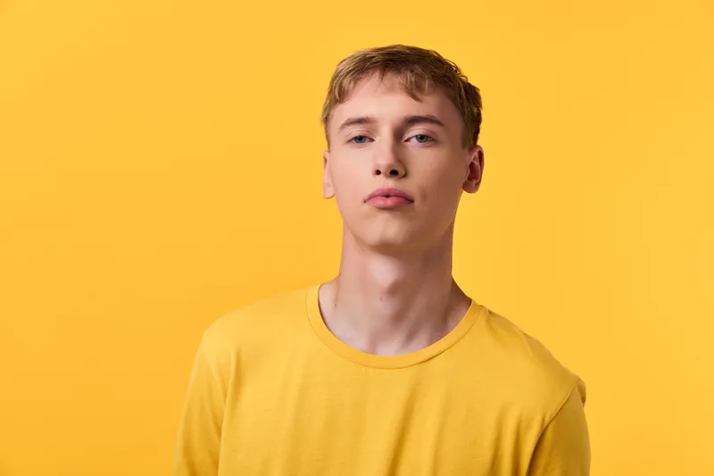Young man wearing a yellow shirt against a yellow background, studio shot with bright lighting and casual mood, ideal for fashion, lifestyle or ad campaigns in stock photography