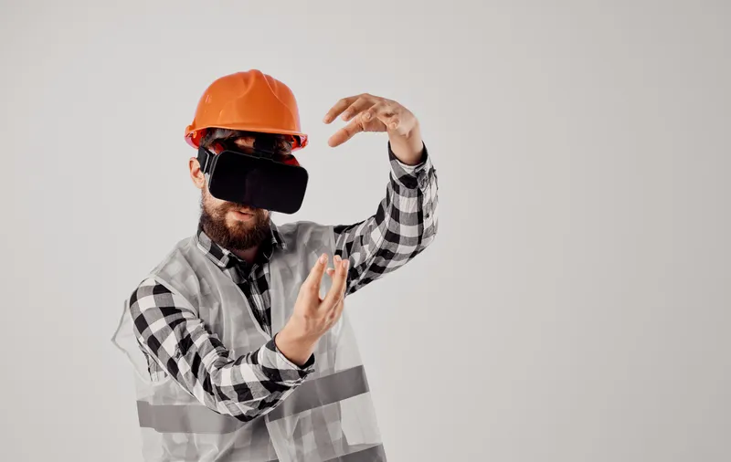 Строитель в оранжевой каске и 3D-очках жестикулирует руками