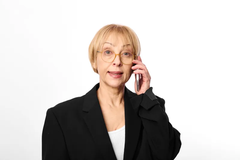 Senior woman, business suit, glasses, phone call, communication, thoughtful look, professional portrait, white studio background, client, customer service, support hotline