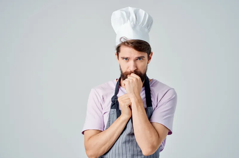 Мужчина в поварской одежде на кухне, работа с продуктами в пищевой промышленности