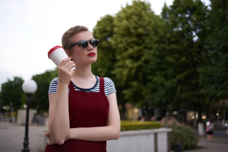 Женщина с короткой стрижкой стоит на улице в солнцезащитных очках