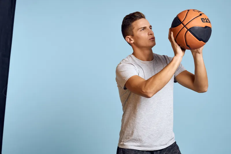 Мужчина с баскетбольным мячом на синем фоне, спорт, игра, модель в белой футболке, энергичный