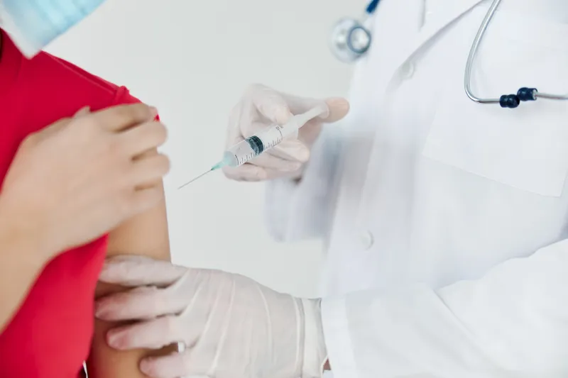 Врач делает инъекцию в плечо, вакцинация от коронавируса, крупный план