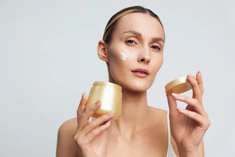 Skincare routine with a moisturizer and face cream, shown in a close-up against a soft neutral backdrop. Emphasizes self care, wellness, beauty, and calm, mindful skincare.