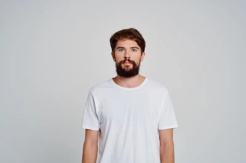 Портрет бородатого мужчины в белой футболке, студийная кадрированная съёмка