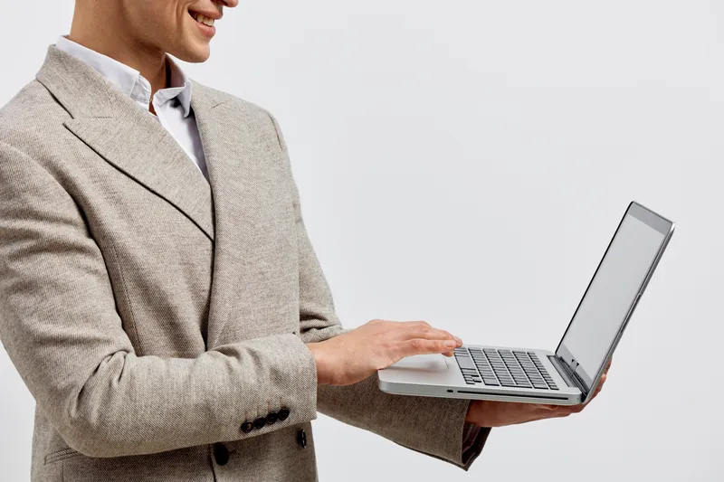 Professional woman in beige blazer holding a laptop computer isolated on plain light grey background with copy space. Business, technology, communication, office, work, business casual, professional c