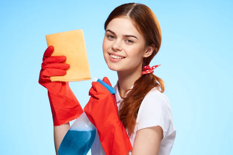 Симпатичная уборщица с чистящими средствами профессионально выполняет свою работу