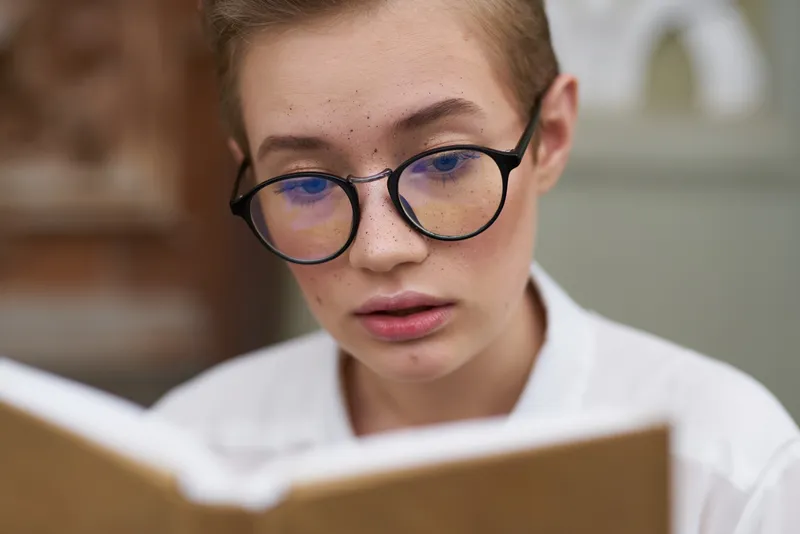 Образованная женщина в очках, студентка возле института с книгой в руках, модель, крупный план