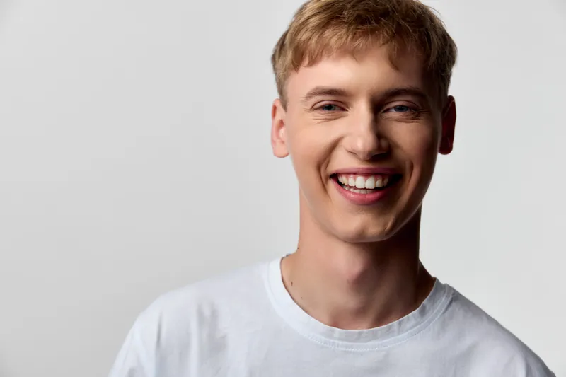Smiling man in a white shirt in a bright studio, conveying friendly energy, approachability, and positive mood suitable for lifestyle, fashion, or advertising campaigns