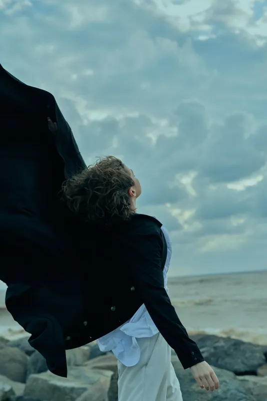 Coast, ocean, wind, jacket, movement, shoreline, outdoors, sea, backdrop, windblown garment travels along the shore as waves crash and clouds drift over a vast horizon by the water