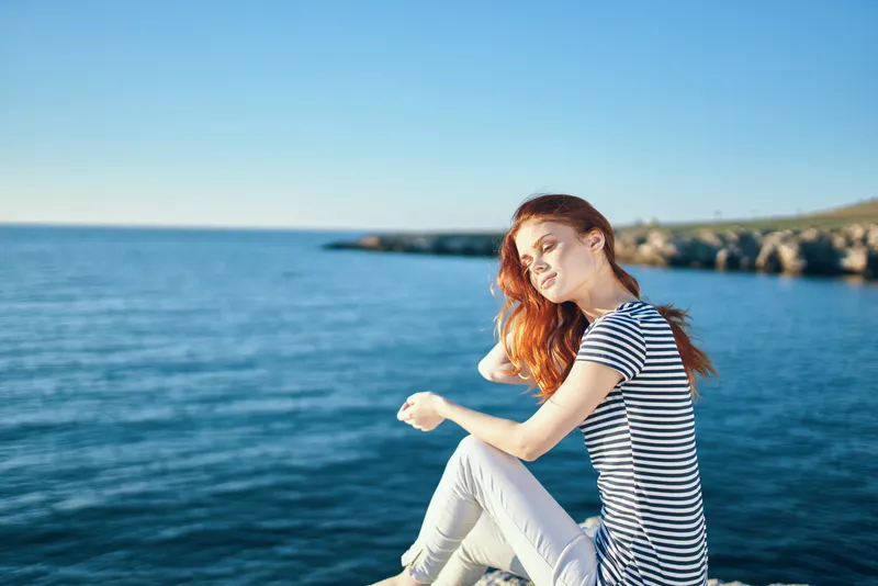 Женщина на скале у моря в горах, закат, лето
