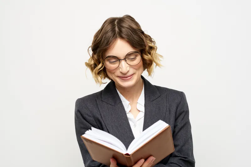 Женщина за работой с книгой в руке на светлом фоне
