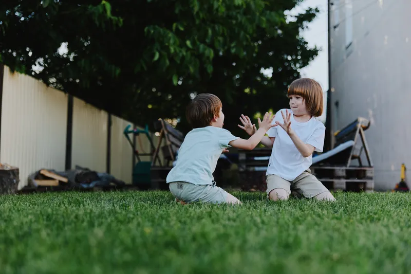 Playful children enjoying a fun game outdoors on a sunny day, engaging in laughter and movement on lush green grass, creating joyful memories together.