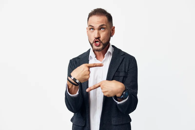 A professional man in a tailored suit, with a surprised expression, frames a moment with his fingers. He stands against an isolated color background, conveying energetic focus and confident emotion.