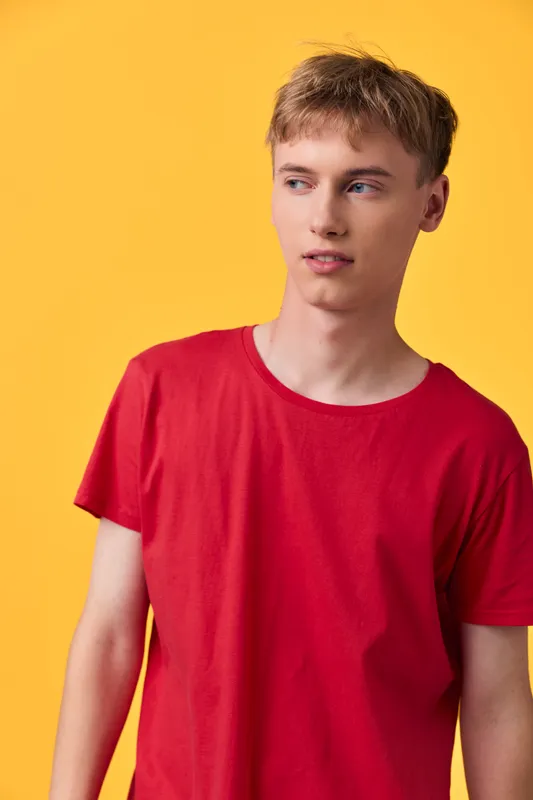 Young man in a red shirt against a bright yellow backdrop, casual fashion and studio shoot for lifestyle use and contemporary style