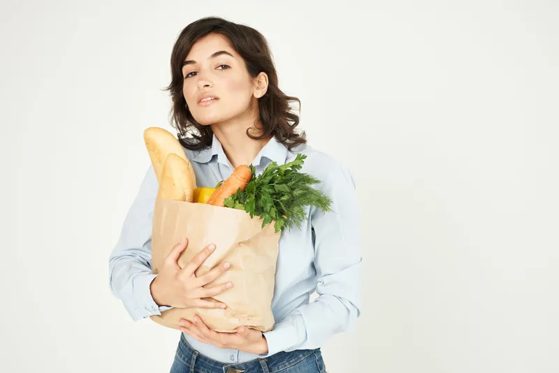 Брюнетка держит продукты, домохозяйка, покупки в супермаркете