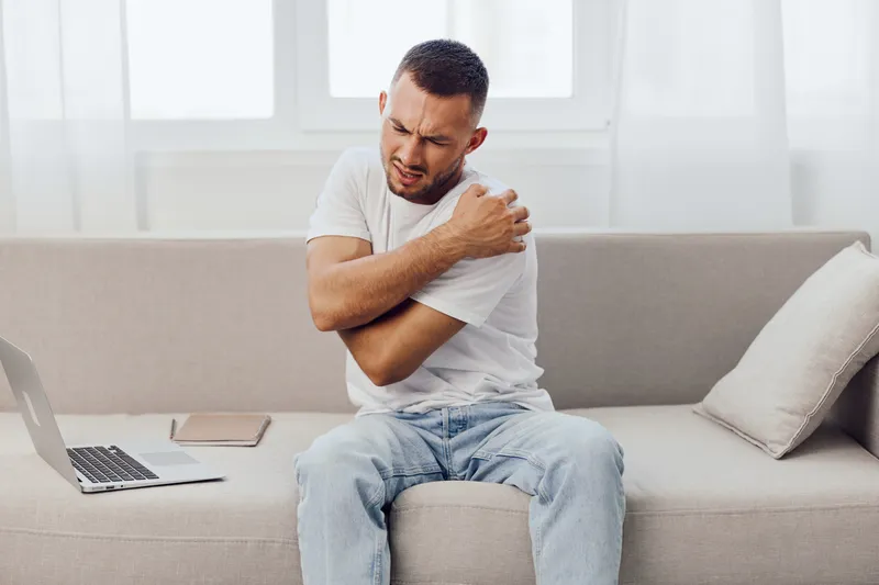 Man experiencing discomfort while managing stress at home, reflecting on the challenges of work-life blur and mental health in the digital age.