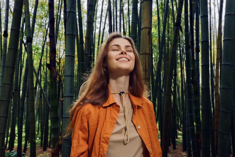 Woman smile bamboo forest nature portrait of a young woman with eyes closed, enjoying a serene outdoor moment in a green grove, peaceful relaxation, natural beauty and calm.