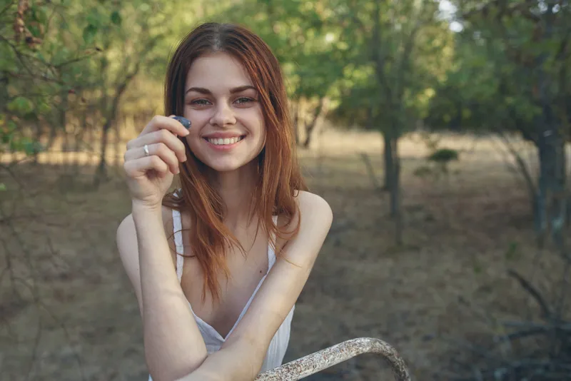 Крупный план женщины в белом платье, которая ест виноград