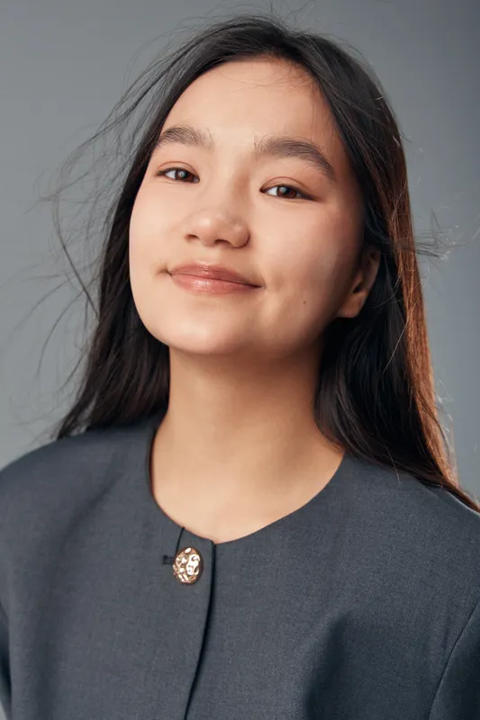 Portrait of young woman with long dark hair smiling softly in casual outfit. Closeup, natural makeup and confident expression with plain light background in studio.
