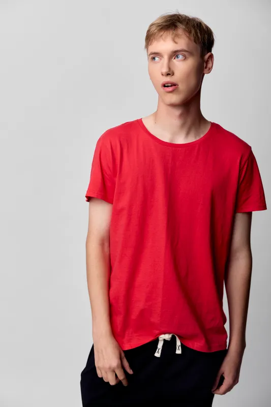 Red t shirt worn by a casual young man, relaxed pose in a studio, highlighting color, comfort and everyday style for fashion and lifestyle stock, ideal for branding, catalog and social media campaigns