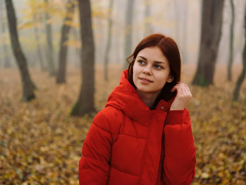 Красивая женщина в красной куртке в осеннем лесу на природе