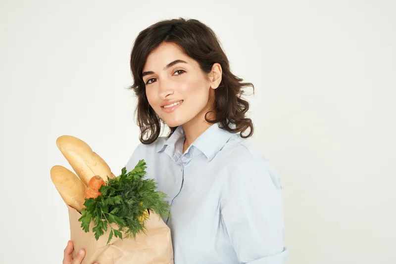 Брюнетка держит продукты в супермаркете, домохозяйка совершает покупки
