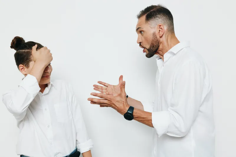 A focused business professional man confronts a puzzled colleague against a plain white background, delivering a passionate message with animated gestures and visible emotion.
