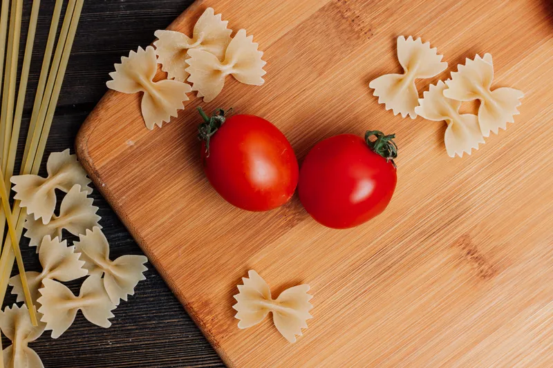 Приготовление итальянской кухни: мука, продукты на кухонном столе, помидоры черри