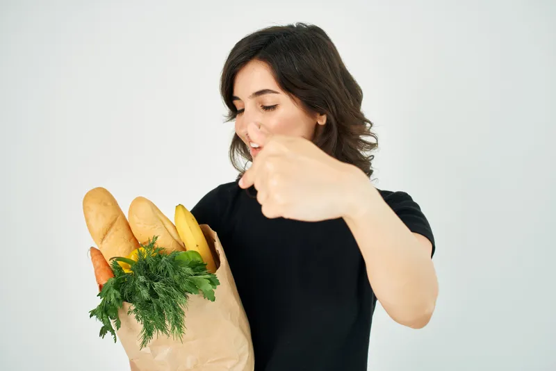 Симпатичная женщина с пакетом продуктов, овощей и полезной еды для доставки