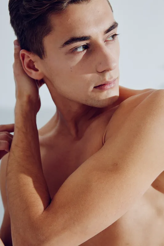 Красивый мужчина с обнаженным торсом смотрит в сторону на светлом фоне