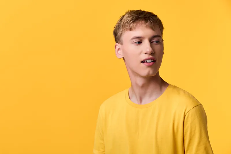 Yellow man shirt in studio setting with bright background, casual fashion vibe, close look at clothing color and expression, warm minimal lighting and modern style
