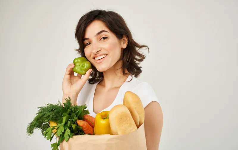 Веселая женщина с пакетом здоровой еды, свежими продуктами