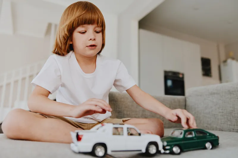 Engaged boy playing with toy cars, showcasing creativity and imagination in a cozy indoor setting filled with warmth and charm.