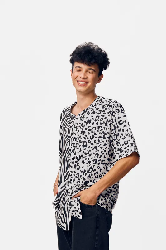 smiling man wearing a black and white patterned shirt with closed eyes, expressing joy and relaxation against a clean white background.