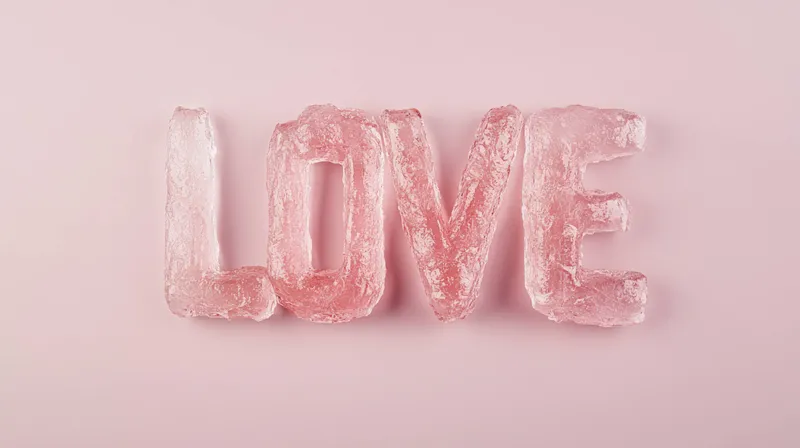 Розовые ледяные буквы образуют слово LOVE на пастельном фоне, символизируя романтику, привязанность и страсть