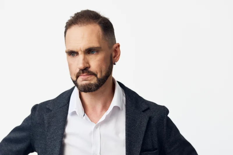 Professional man in business attire against an isolated colored background, exuding confidence, focus, and calm determination with a thoughtful expression.