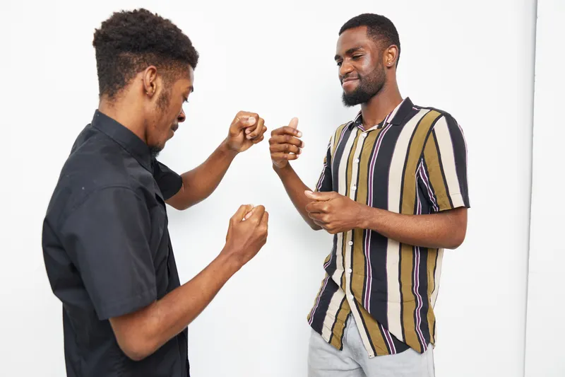 Two black men engaging in a fun game of rock-paper-scissors, showcasing friendly competition and joy. Their expressions reflect excitement and camaraderie.