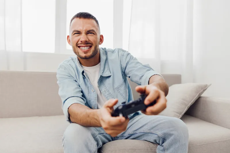 Engaged man enjoying video games at home, showcasing emotional minimalism, soft masculinity, and a modern approach to solo living.
