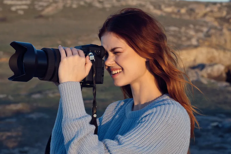 Женщина с фотоаппаратом на природе снимает пейзаж