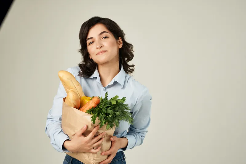 Женщина в синей рубашке с пакетом продуктов делает покупки в супермаркете