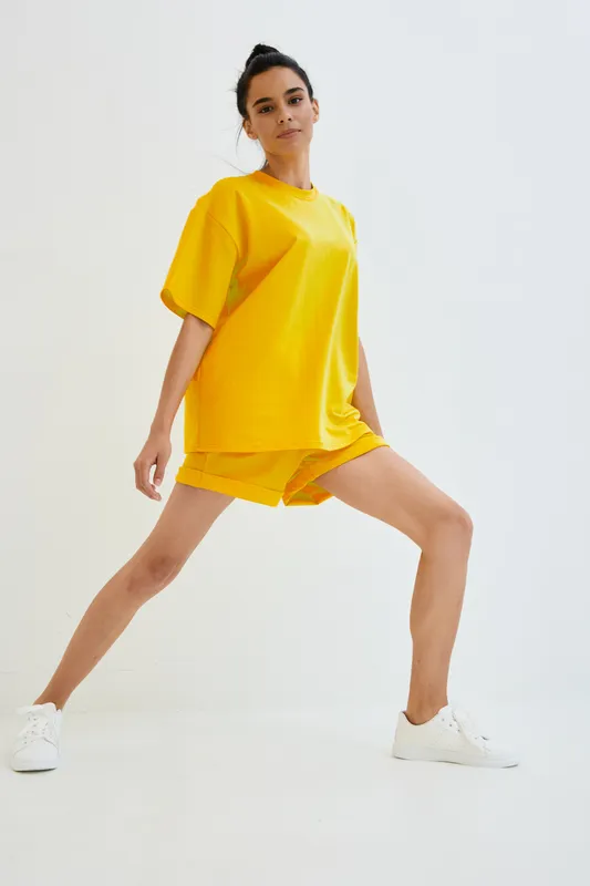 young woman in bright yellow casual outfit stretching legs in dynamic pose, isolated on white background, athletic and active lifestyle concept