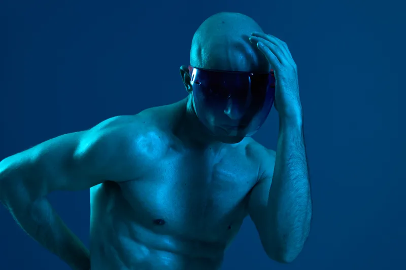 A contemplative man in a blue light, wearing a visor, posing thoughtfully. The image exudes a modern, mysterious vibe, perfect for futuristic themes.