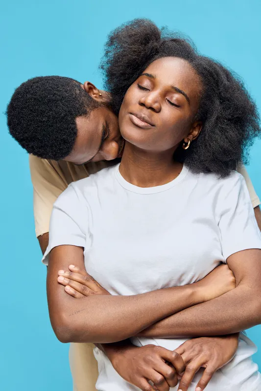 Romantic couple embracing against a bright blue background, showcasing love and intimacy with soft emotions in summer attire
