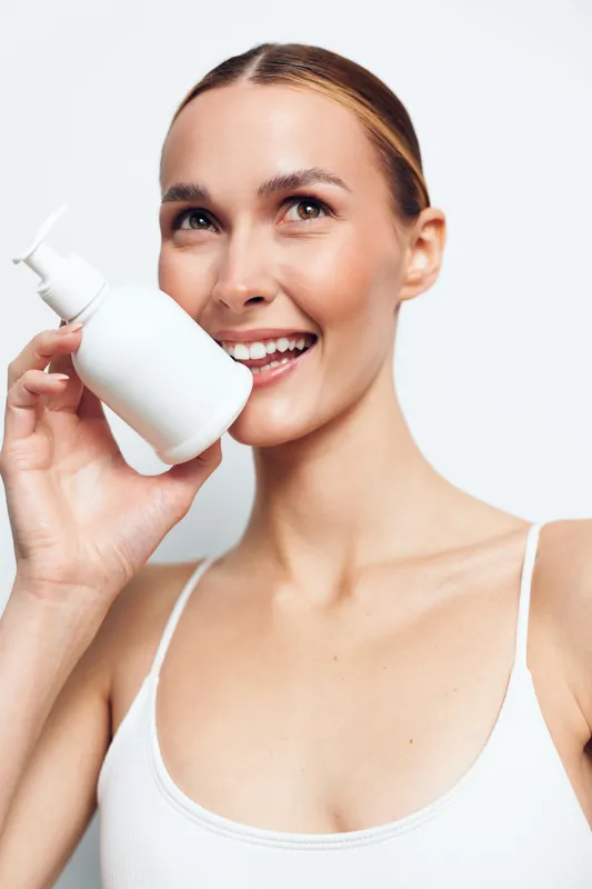 Woman beauty cosmetics skincare mist spray smile studio portrait, young woman holds white spray bottle of face mist, fresh skincare and personal hygiene, clean isolated background, close up beauty