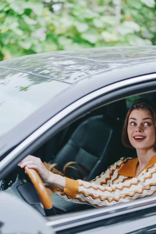 Car, driver, woman, smile a cheerful woman sits behind the wheel with a confident smile in the car interior, ready for a journey and enjoying a moment of happiness on the road