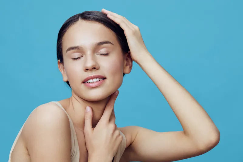 Beautiful young woman with closed eyes poses against a blue background, showcasing natural beauty and tranquility in a minimalistic style, emphasizing wellness and self care